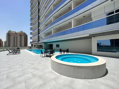 a large building with a pool and tables and chairs at Stylish Studio Urban Retreat in Dubai
