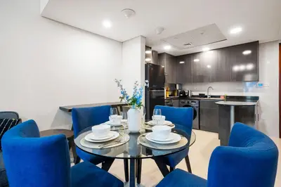 a dining room with a table and blue chairs at StoneTree - Cozy 1 BR - Near Metro in Dubai