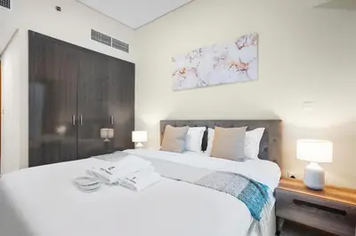 a bedroom with a large white bed with two lamps at StoneTree - Cozy 1 BR - Near Metro in Dubai