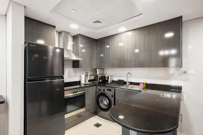 a kitchen with a black refrigerator and a dishwasher at StoneTree - Cozy 1 BR - Near Metro in Dubai