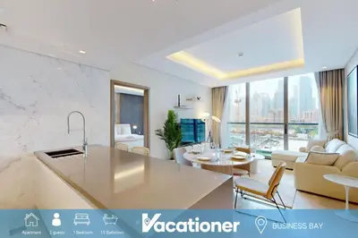a kitchen and living room with a couch and a table at The Sterling - Modern One Bedroom in Dubai