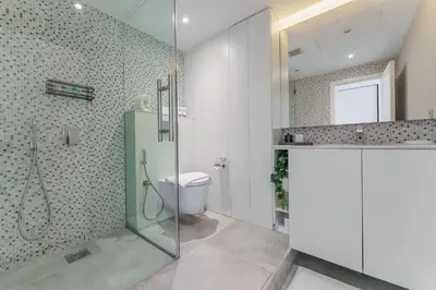 a bathroom with a glass shower and a toilet at Prime Downtown 2BR Retreat in Dubai