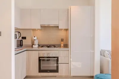 a kitchen with white cabinets and a stove top oven at Sobha waves I Cozy 1BDR I Burj Khalifa View in Dubai