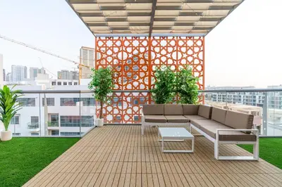 a rooftop patio with a couch and plants on a building at Upgraded Designer-crafted Studio in JVC with Massive Terrace in Dubai