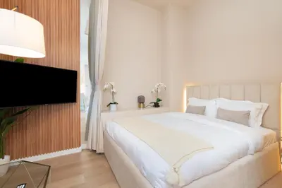 a bedroom with a white bed and a flat screen tv at Upgraded Designer-crafted Studio in JVC with Massive Terrace in Dubai
