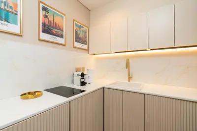 a kitchen with white cabinets and a sink at Upgraded Designer-crafted Studio in JVC with Massive Terrace in Dubai