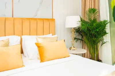 a bed with white and orange pillows and a plant at Elite Royal Apartment - Sky Series - Full Panoramic Burj Khalifa & Fountain View - Icon in Dubai