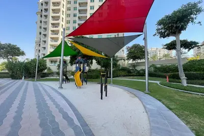 a playground with a red and yellow umbrella and a slide at Exquisite 1BR with Private beach in Palm Jumeirah in Dubai