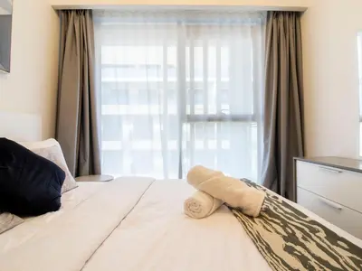 a bed with a towel on it with a window at Spacious 2BR with Big Balcony In Meydan in Dubai