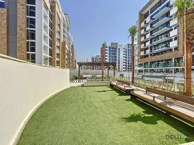 a park with benches and grass in a city at Delightful 1BR Apartment in Azizi Riviera 22, Al Merkadh by Deluxe Holiday Homes in Dubai