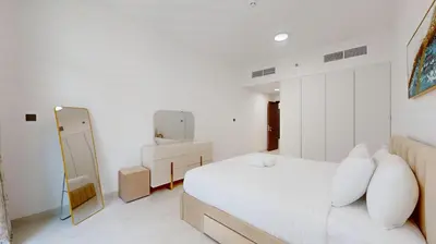 a white bedroom with a bed and a mirror at Locations I Uni Estate Supreme Residence I Luxury 1BR I Near Miracle Garden I Pool, Gym & Parking in Dubai