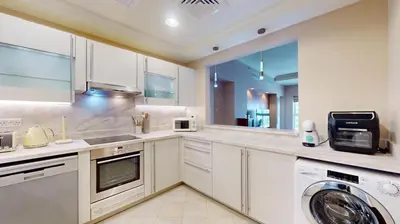 a kitchen with white cabinets and a washer and dryer at Golden Mile 1 - Contemporary One Bedroom in Dubai