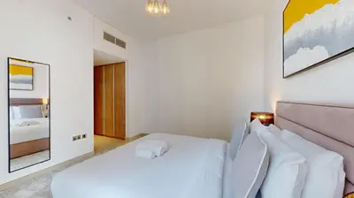 a white bedroom with a bed and a mirror at Liv Residences - Spacious Two Bedroom in Dubai