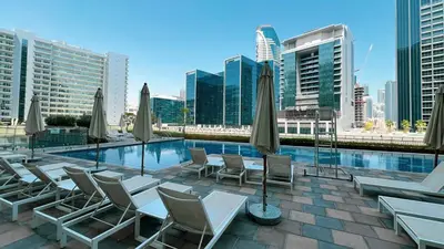 a pool with chairs and umbrellas on a building at LUXE | 1BR | Close to Burj Khalifa & Dubai Mall in Dubai