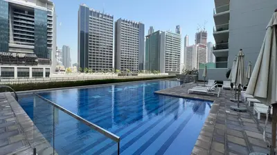 a large swimming pool in a city with tall buildings at LUXE | 1BR | Close to Burj Khalifa & Dubai Mall in Dubai