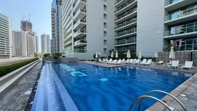 a large swimming pool with chairs and a building at LUXE | 1BR | Close to Burj Khalifa & Dubai Mall in Dubai