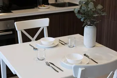 a white table with plates and a vase of flowers at LUXE | 1BR | Close to Burj Khalifa & Dubai Mall in Dubai