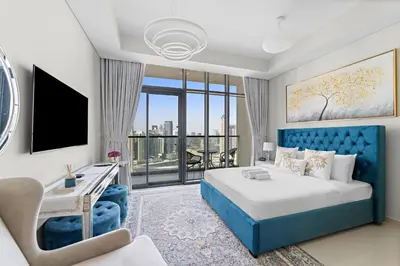 a hotel room with a blue bed and a desk at Lush studio with Pool & Dubai Water Canal Views in Dubai