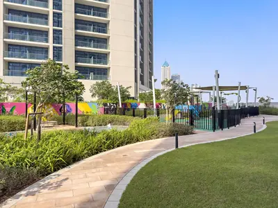 a park in front of a building with a playground at Lush studio with Pool & Dubai Water Canal Views in Dubai