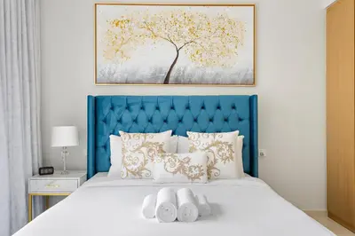 a bedroom with a blue headboard and a white bed at Lush studio with Pool & Dubai Water Canal Views in Dubai