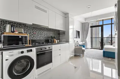 a white kitchen with a washer and dryer in it at Lush studio with Pool & Dubai Water Canal Views in Dubai