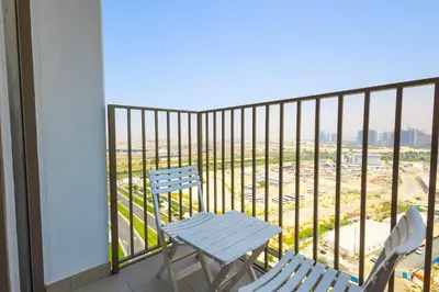 two chairs and a table on a balcony at Socio Tower1 - Dubai Hills Modern Urban Retreat in the City by Serenity Living Holiday Homes in Dubai