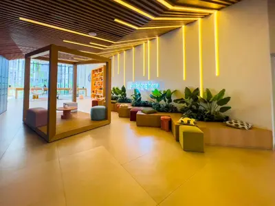 a lobby with couches and plants in a building at Socio Tower1 - Dubai Hills Modern Urban Retreat in the City by Serenity Living Holiday Homes in Dubai