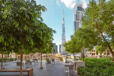 a patio with tables and trees and a view of a city at Elite Royal Apartment - Sky Series - Full Burj Khalifa & Fountain View - Noble in Dubai
