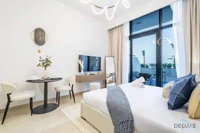 a bedroom with a white bed and a table and chairs at Stylish Studio Apartment in Azizi Riviera 37 Al Merkadh by Deluxe Holiday Homes in Dubai