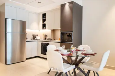 a kitchen with a table and chairs and a refrigerator at Manzil - 1BR Apartment in Marquis Signature with City Views in Dubai