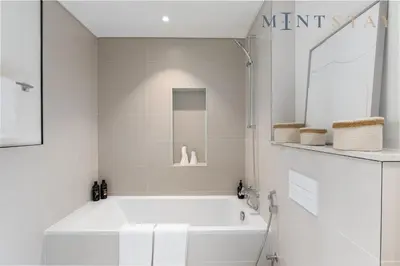 a white bathroom with a tub and a mirror at Marina Vista 2, Emaar Beachfront - Mint Stay in Dubai