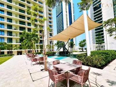 a patio with tables and chairs and an umbrella at Marina Vista 2, Emaar Beachfront - Mint Stay in Dubai