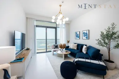 a living room with a blue couch and a tv at Marina Vista 2, Emaar Beachfront - Mint Stay in Dubai