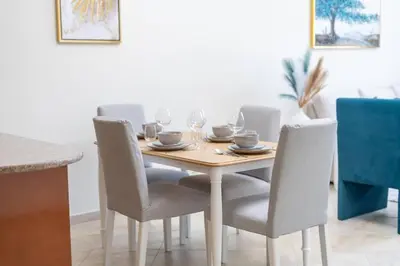 a dining room table with chairs and a wooden table with wine glasses at Peaceful flat in Motor City in Dubai