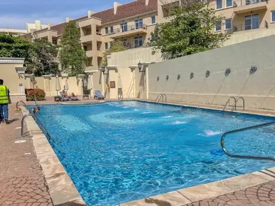 a large blue swimming pool in front of a building at Peaceful flat in Motor City in Dubai