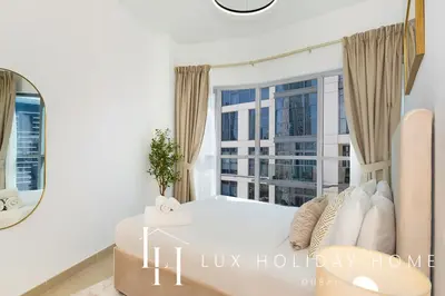 a white bedroom with a large window and a bed at LUX The Executive Burj Khalifa View Suite in Dubai
