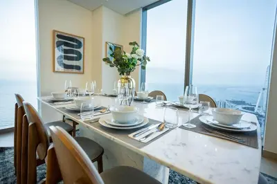 a long table with chairs and a vase of flowers at Waves - 52 42 Emaar, Tower 1 in Dubai