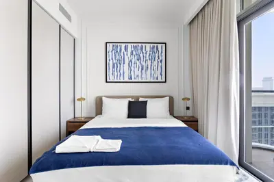 a bedroom with a blue and white bed and a window at Silkhaus Sea View Stunning 1BDR with Private Beach in Dubai