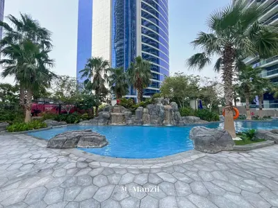 a pool in the middle of a city with palm trees at Manzil - 1BR Apartment in Paramount with Top-Floor Luxury Living in Dubai