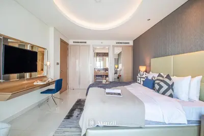 a bedroom with a large bed with a desk and a television at Manzil - 1BR Apartment in Paramount with Top-Floor Luxury Living in Dubai