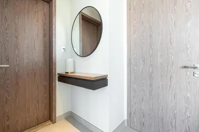 a bathroom with a wooden door and a mirror at Vacay Lettings - Liv Residence in Dubai