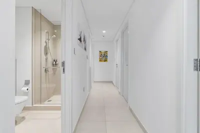 a white bathroom with a hallway with a toilet and a sink at New Stunning 4 BR Burj Khalifa View in Dubai