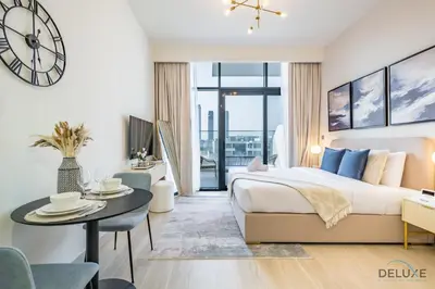 a bedroom with a bed and a table and a clock at Delightful Studio Apartment in Azizi Riviera 20, Al Merkadh by Deluxe Holiday Homes in Dubai