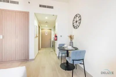 a dining room with a table and chairs and a clock on the wall at Delightful Studio Apartment in Azizi Riviera 20, Al Merkadh by Deluxe Holiday Homes in Dubai