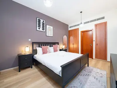 a bedroom with a large bed and a wooden door at Stylish One Bedroom Sanctuary in the Greens in Dubai