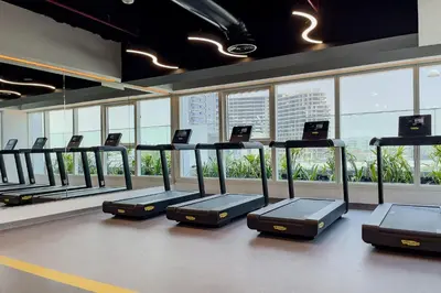 a gym with a row of treadmills and windows at Apartments in ME DO RE Jumeirah Lake Towers in Dubai