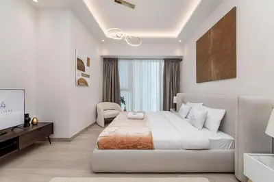 a white bedroom with a large bed and a window at Apartments in ME DO RE Jumeirah Lake Towers in Dubai