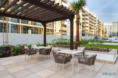 a patio with tables and chairs under a pergola at Captivating 1BR Apartment in Azizi Riviera 20, Al Merkadh by Deluxe Holiday Homes in Dubai
