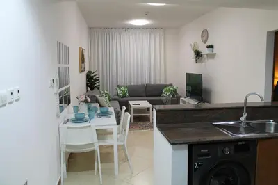 a kitchen and living room with a table and chairs at Bright and beautiful one bedroom apartment close to metro and beach in Dubai