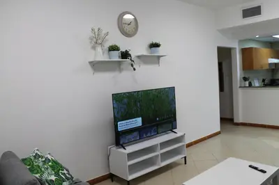 a living room with a flat screen tv on a wall at Bright and beautiful one bedroom apartment close to metro and beach in Dubai
